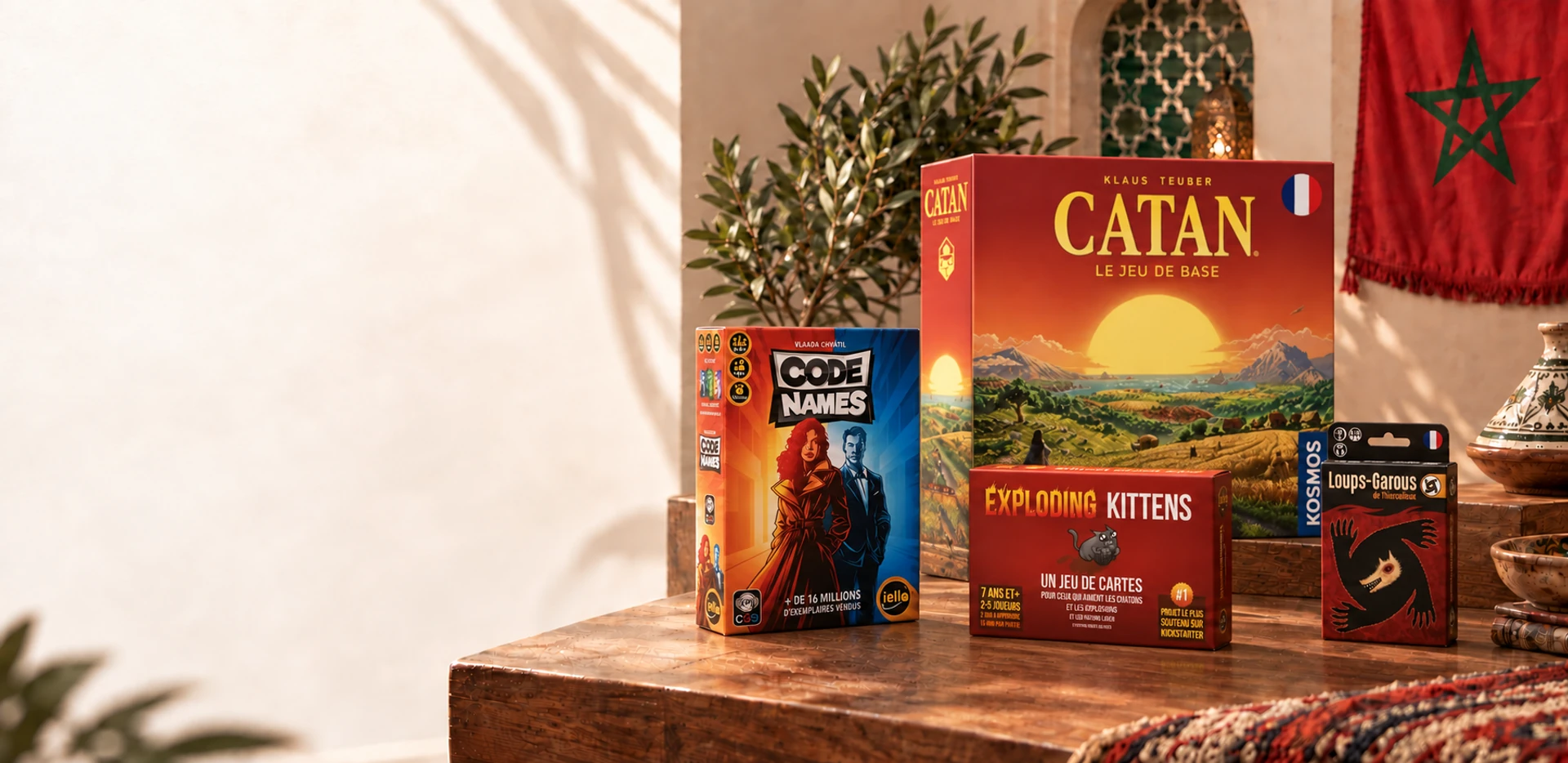 Catan, Code Names, Exploding Kittens et Les Loups-Garous réunis sur une table en bois, dans un décor marocain.